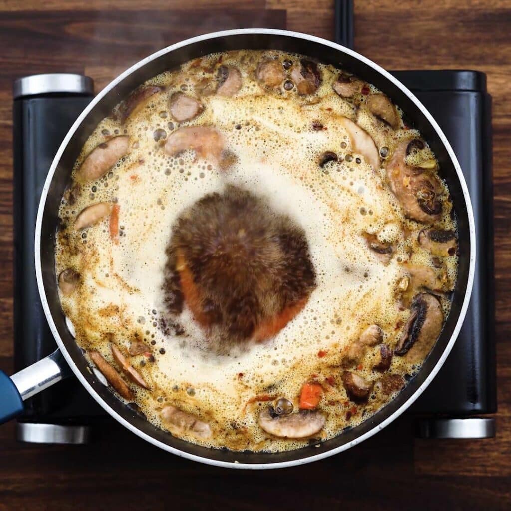 A pan with chicken broth and veggies boiling.