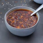 Chili Oil in a white bowl with few ingredients scattered around.