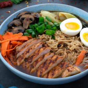 Homemade Ramen in a bowl with sliced chicken breast, boiled egg and veggies.