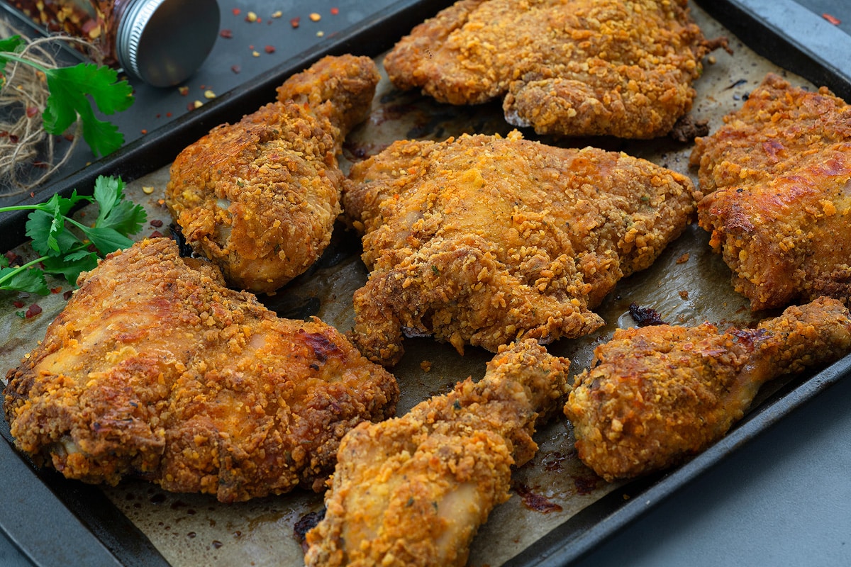 Healthy Oven-Fried Chicken on a baking tray with sliced lemon.