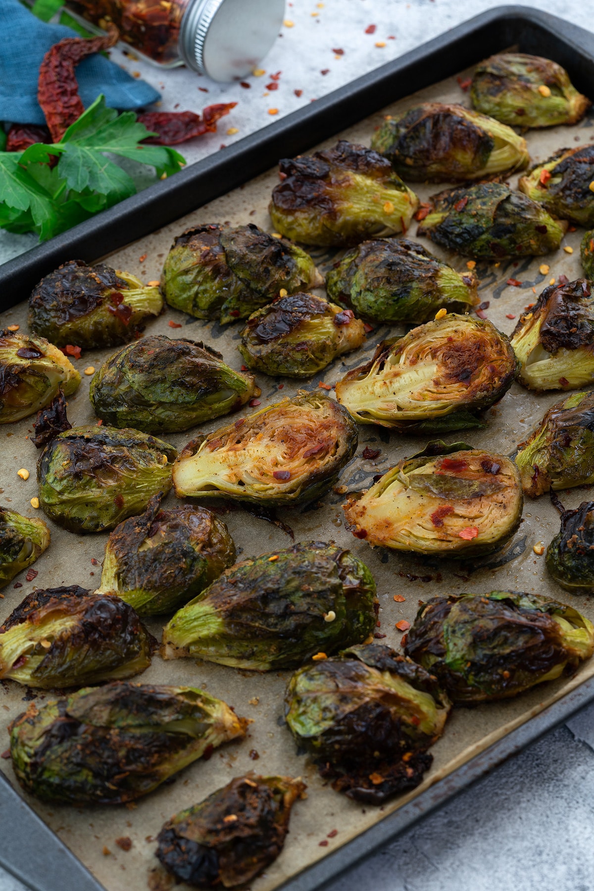 Oven Roasted Brussels Sprouts in a baking tray with few ingredients scattered around.