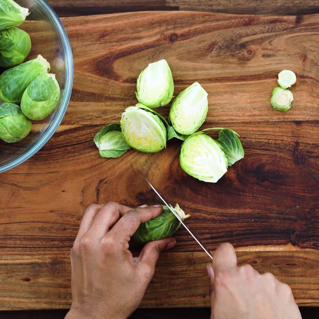 Chopping the brussels sprouts in half using a knife.