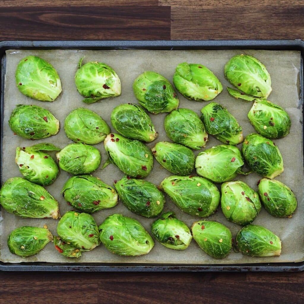 A baking tray with seasoned brussels sprouts.