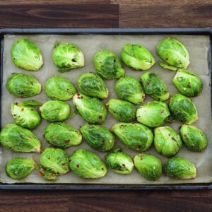 A baking tray with seasoned brussels sprouts.