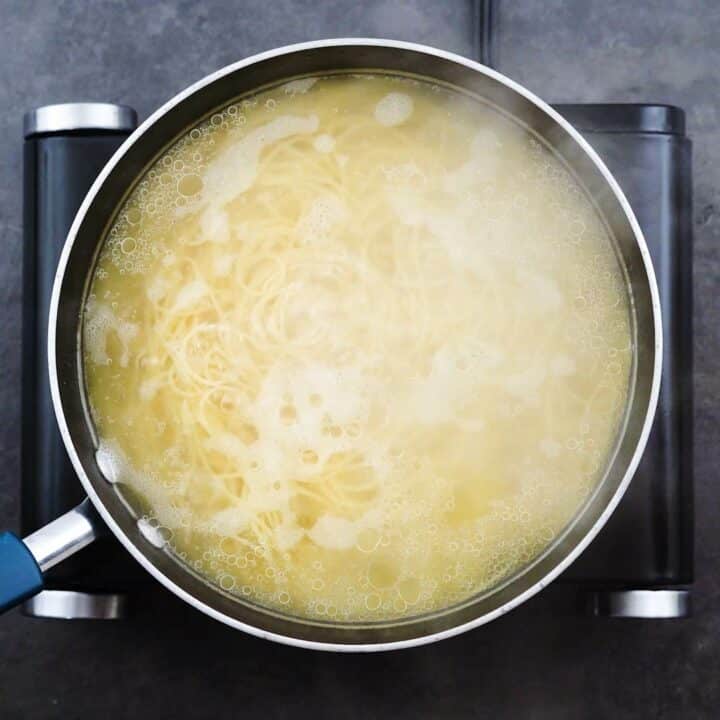 A pot with pasta cooking in hot water.