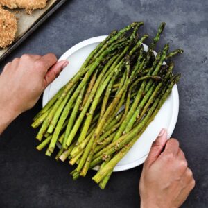 Serving the Sauteed Asparagus in a white plate.