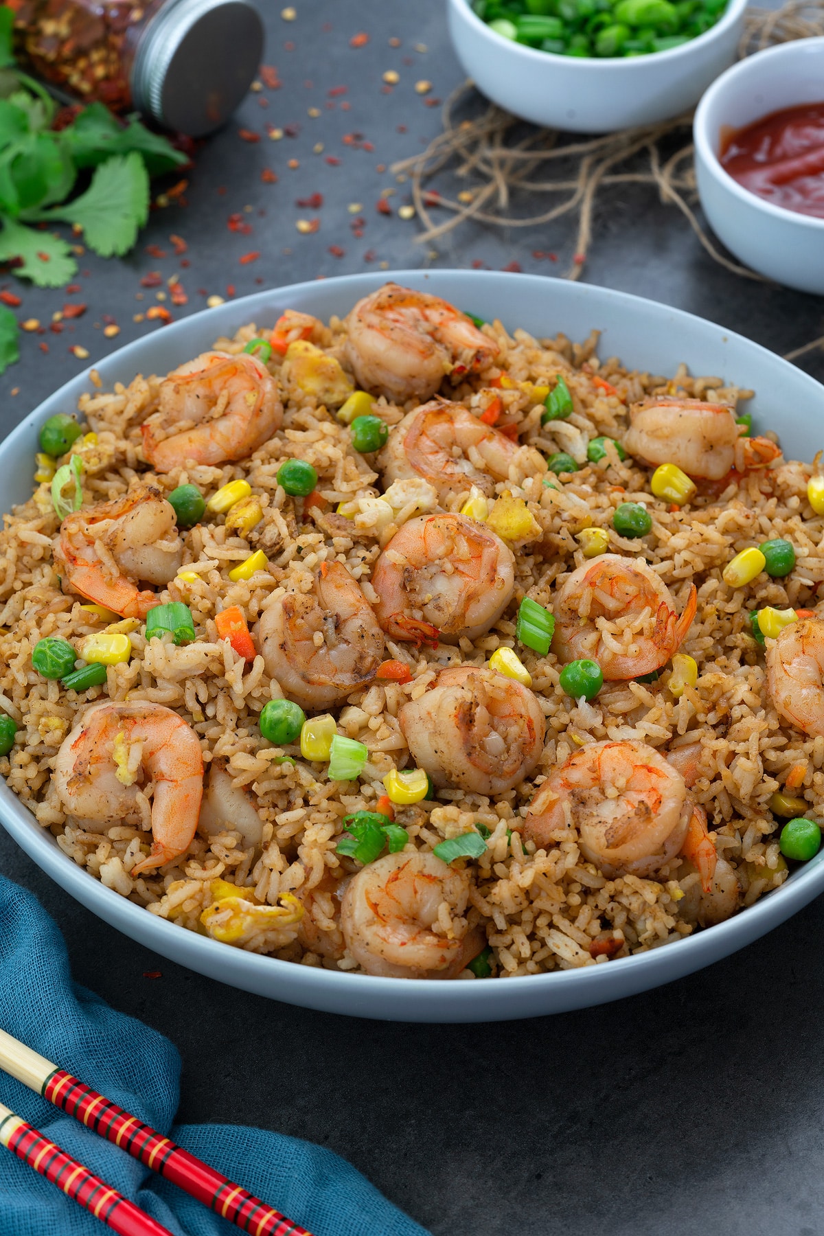 Shrimp Fried Rice in a white plate with few ingredients scattered around.