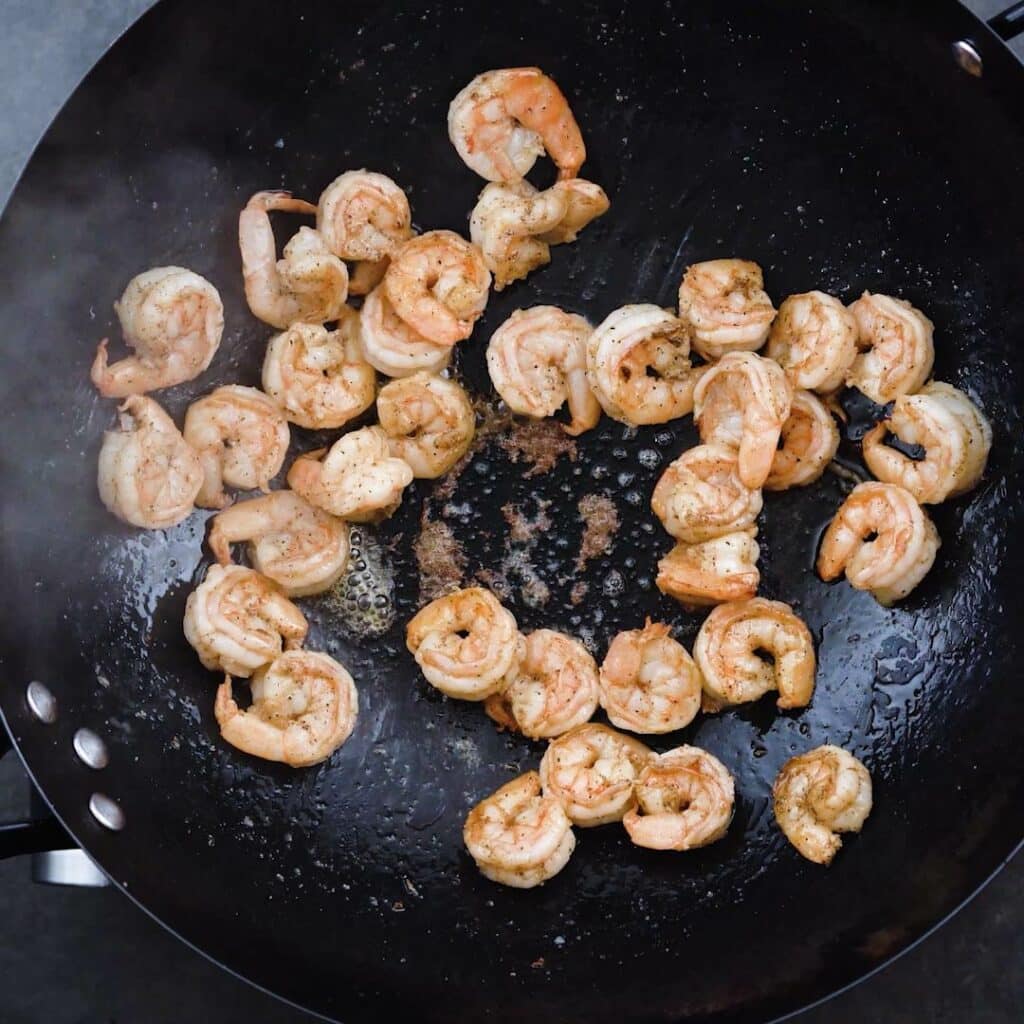 A wok with shrimp cooking.