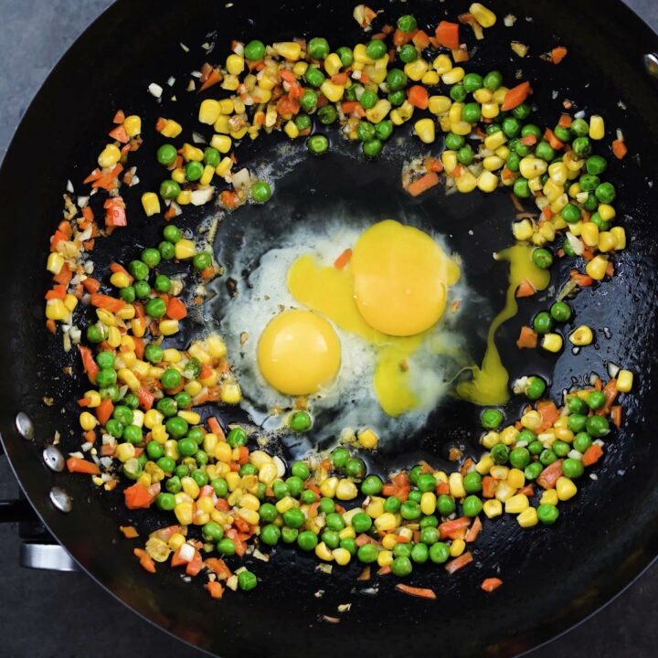 A wok with egg and veggies.