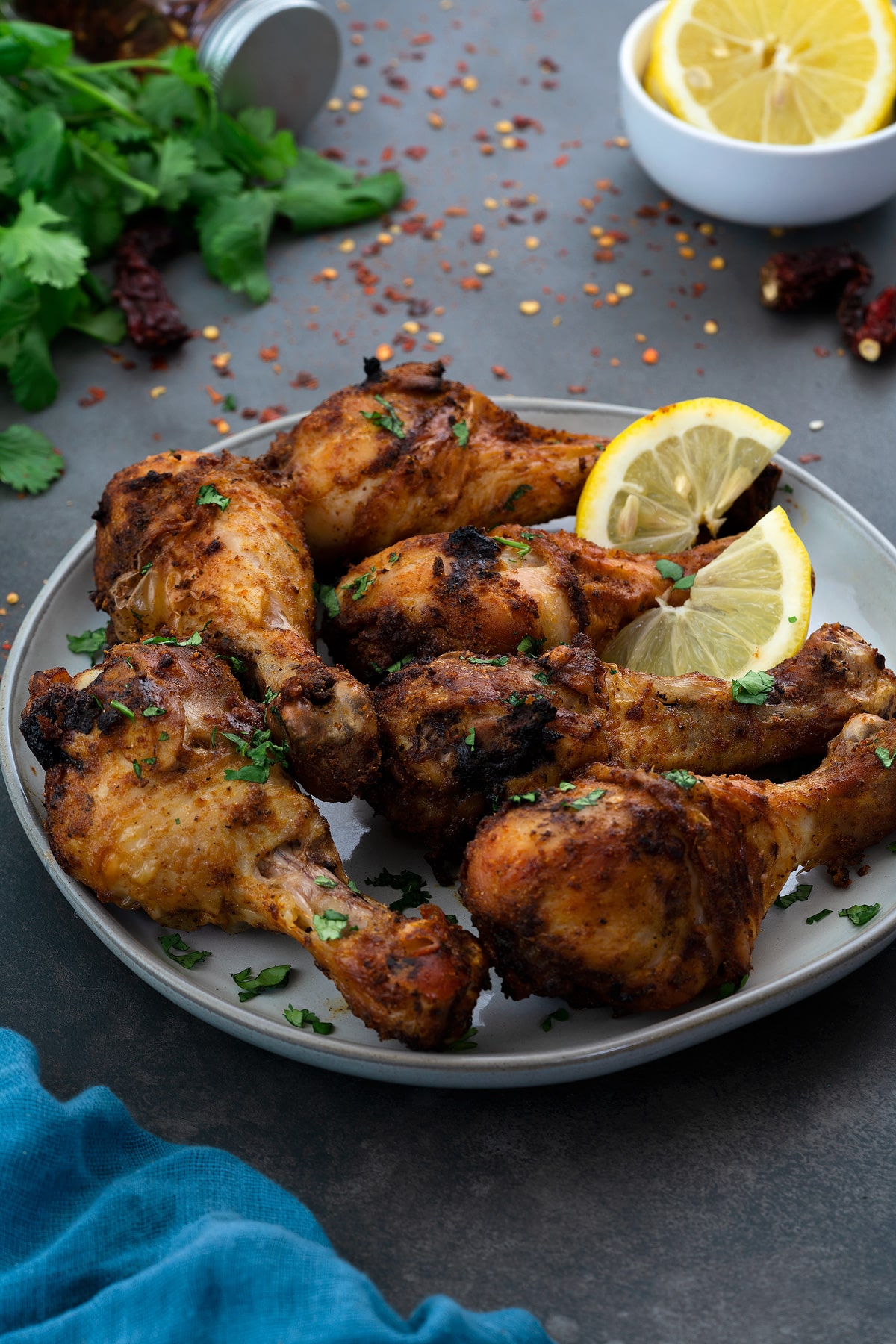 Air Fryer Chicken Legs (Drumsticks) served in a white plate with few ingredients scattered around.