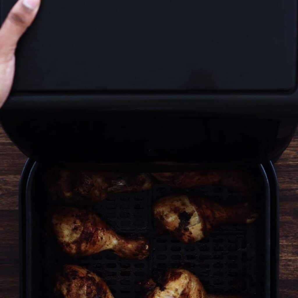 Air Fryer basket with fried chicken legs.