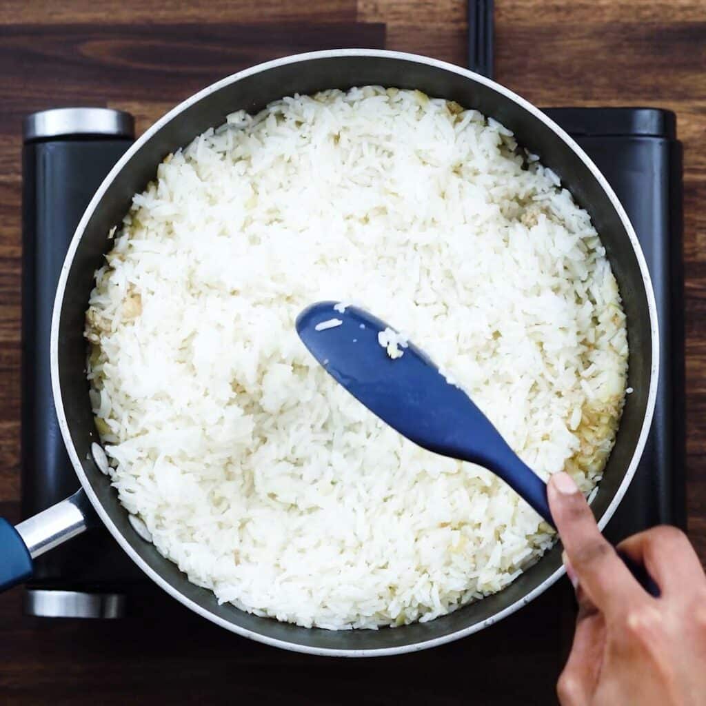 Fluffing the cooked rice using a spatula.