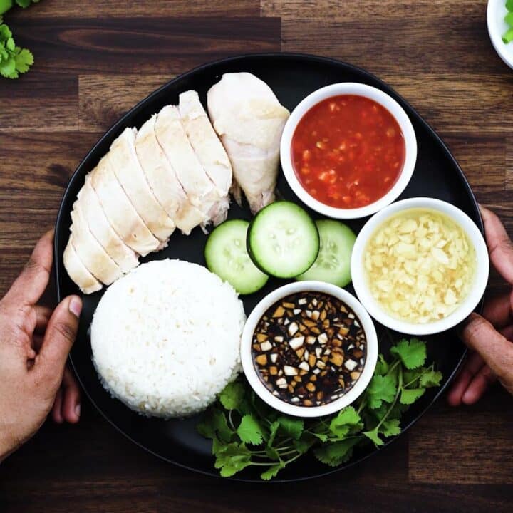 Serving the Hainanese Chicken Rice in a black plate with cucumber and cilantro.