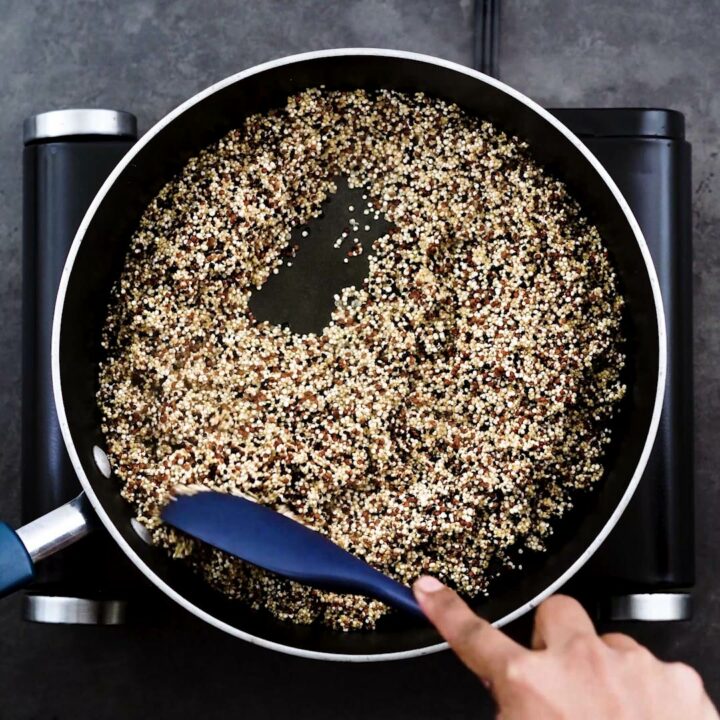 Toasting quinoa in a wide pan.