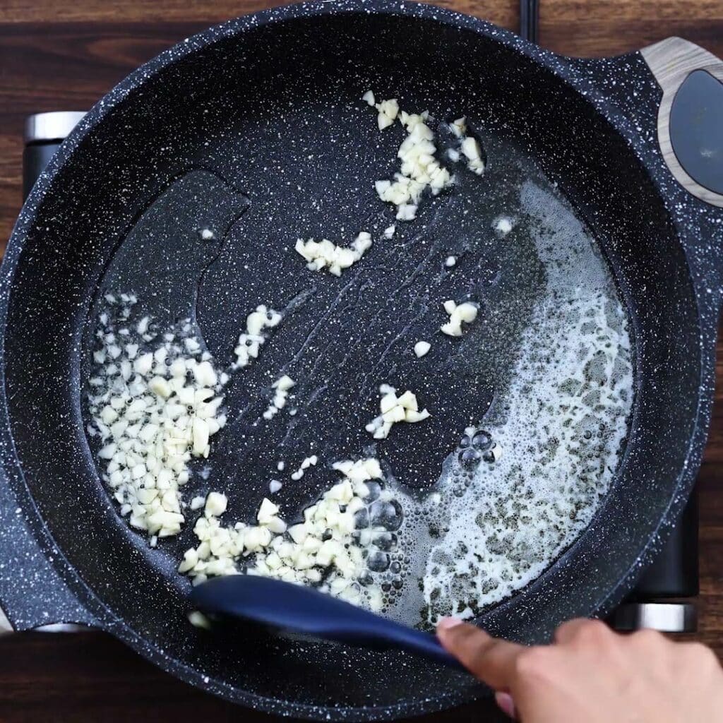 Sautéing garlic in a wide pan.