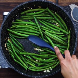 Sauteing green beans in a pan.