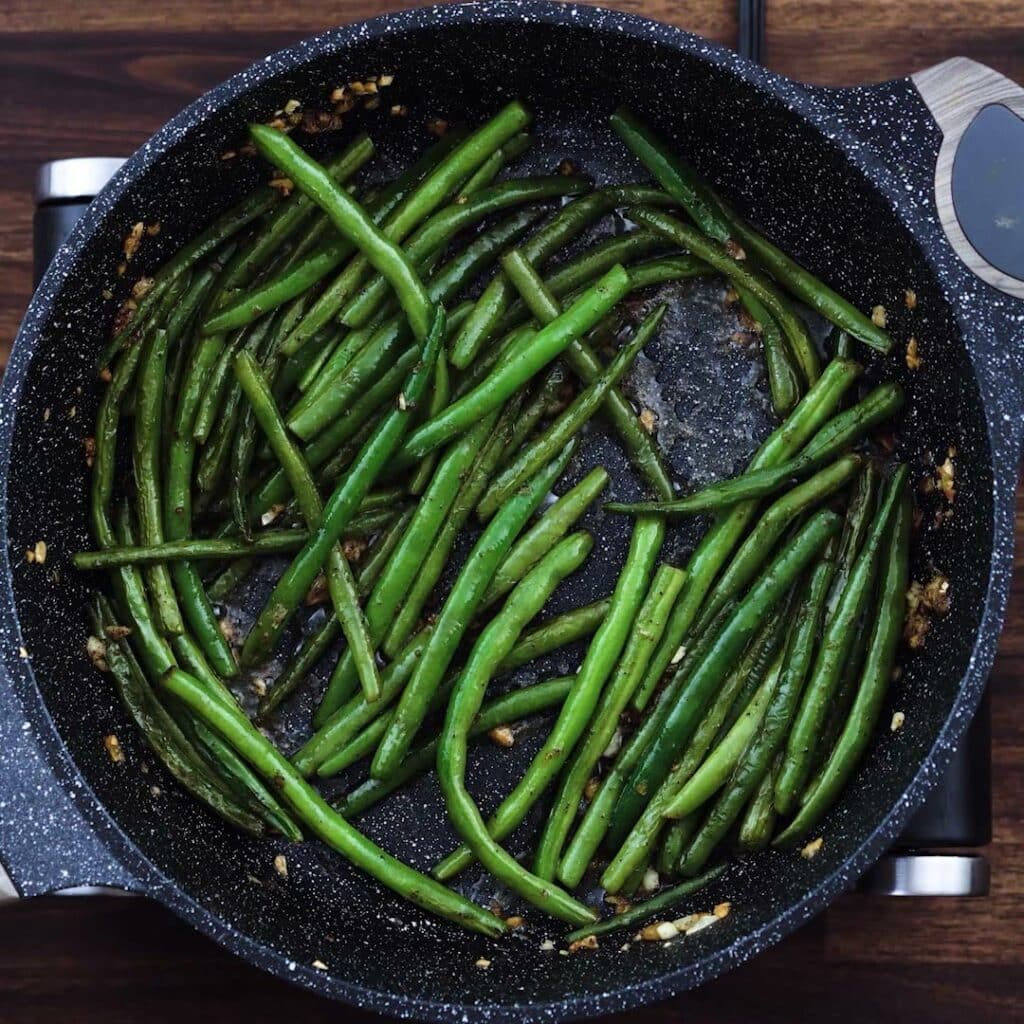 Sauteed green beans in a pan.