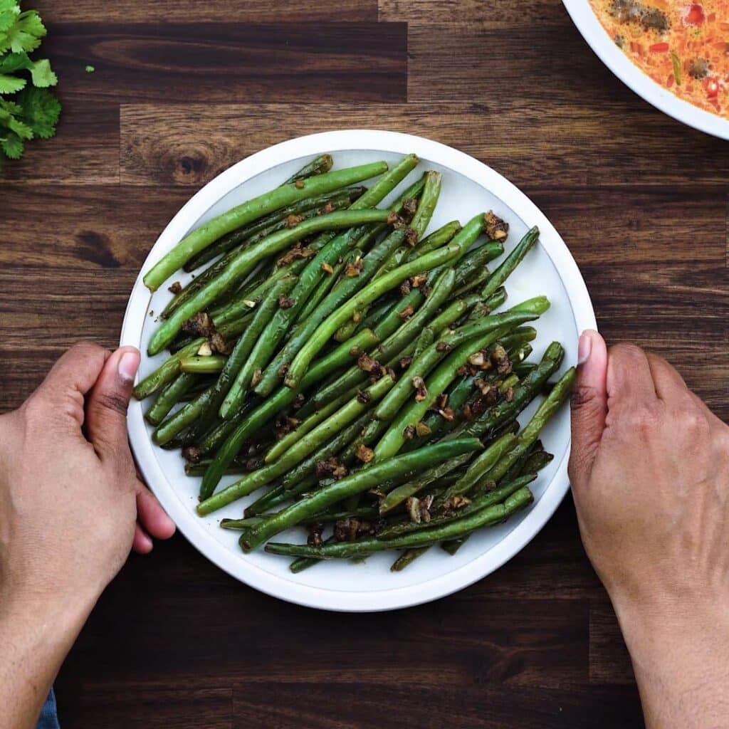 Serving sauteed green beans in a white serving plate.