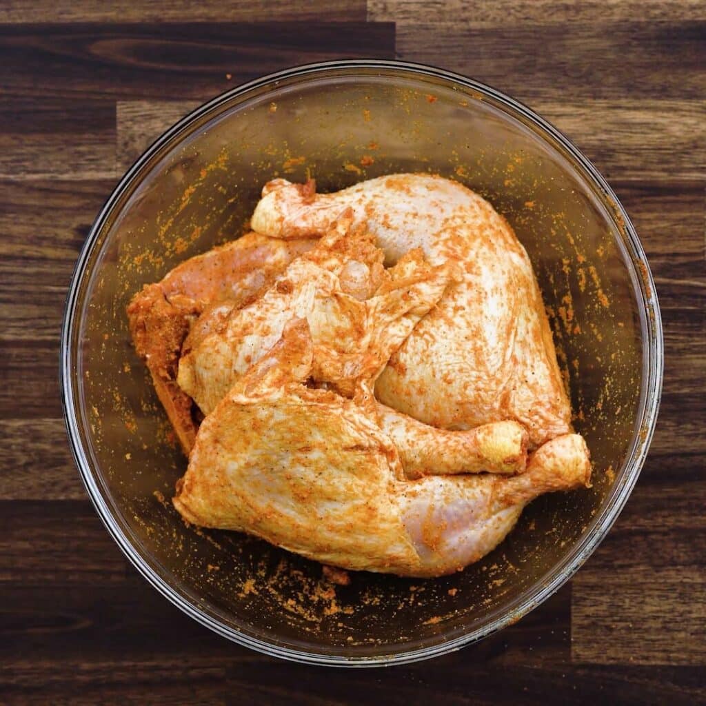 A bowl with seasoned chicken leg quarters.