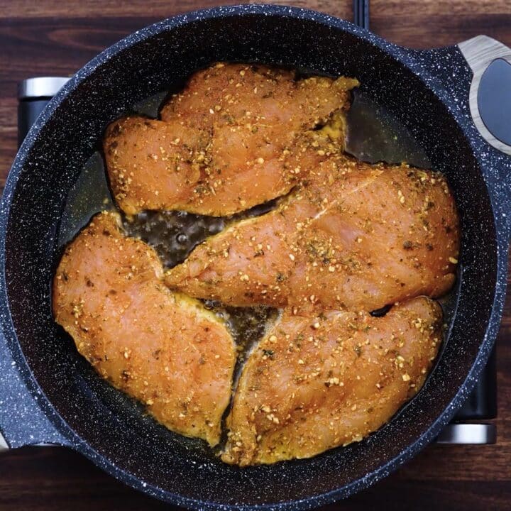 Frying the chicken breast in a pan.