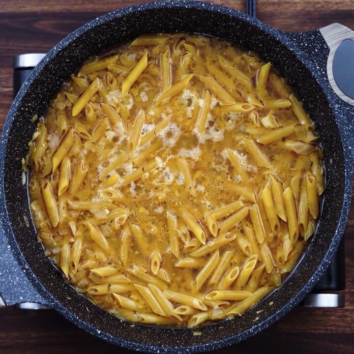 A pan with pasta cooking in a chicken broth.