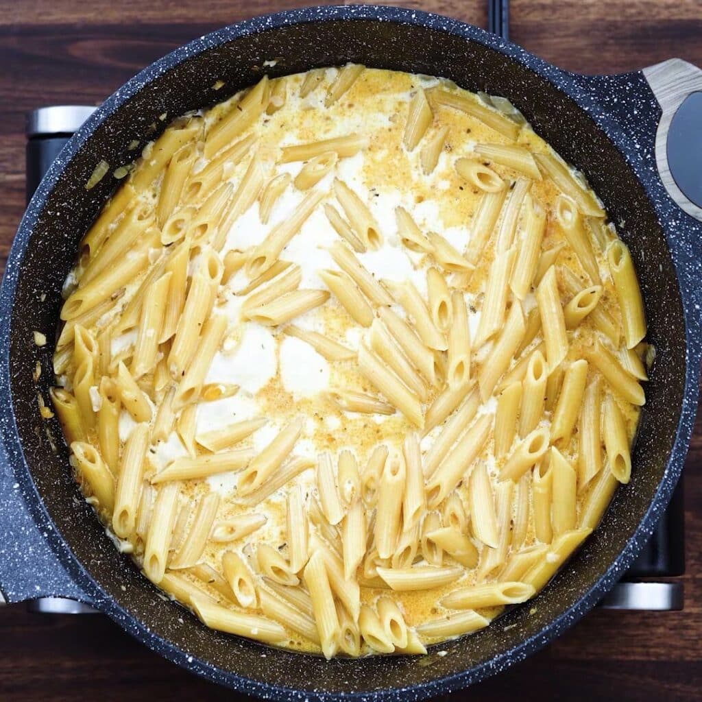 A pan with pasta cooking in a heavy cream mixture.