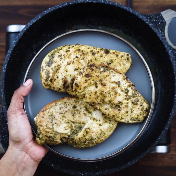 Nicely fried basil pesto chicken on a grey plate.
