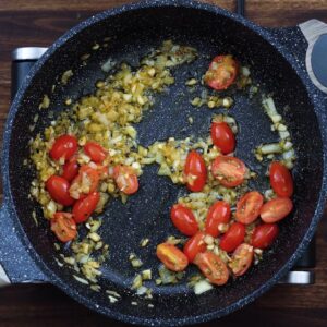 Aromatics and cherry tomatoes in a pan.