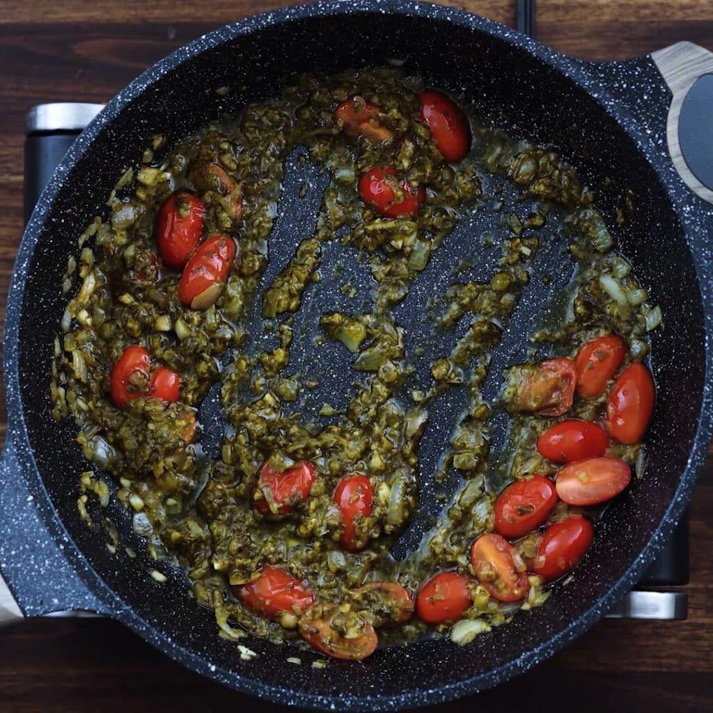 A pan with mixture of basil pesto, cherry tomatoes and aromatics.