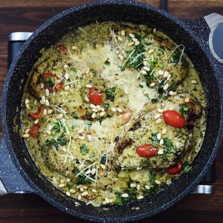 Creamy Pesto Chicken garnished with pine nuts, parmesan cheese, and basil leaves.