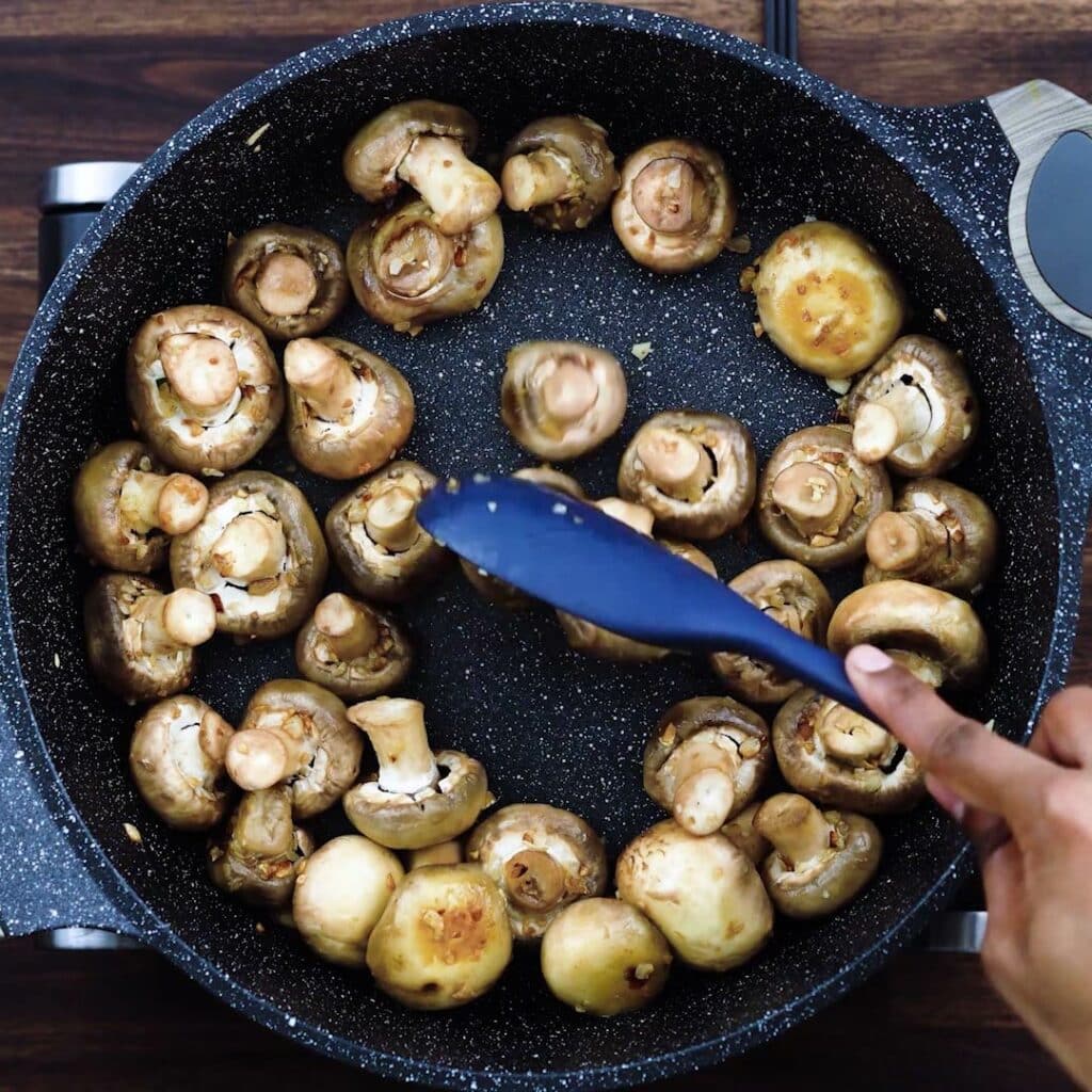 Sauteing mushrooms in wide pan.
