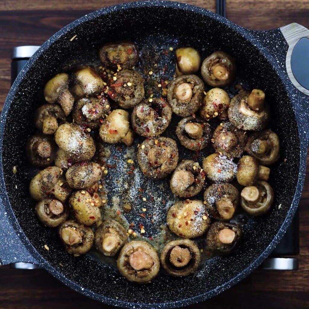 Mushrooms with seasonings in a pan.