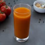 Homemade Tomato Juice in a glass with few ingredients arranged around.
