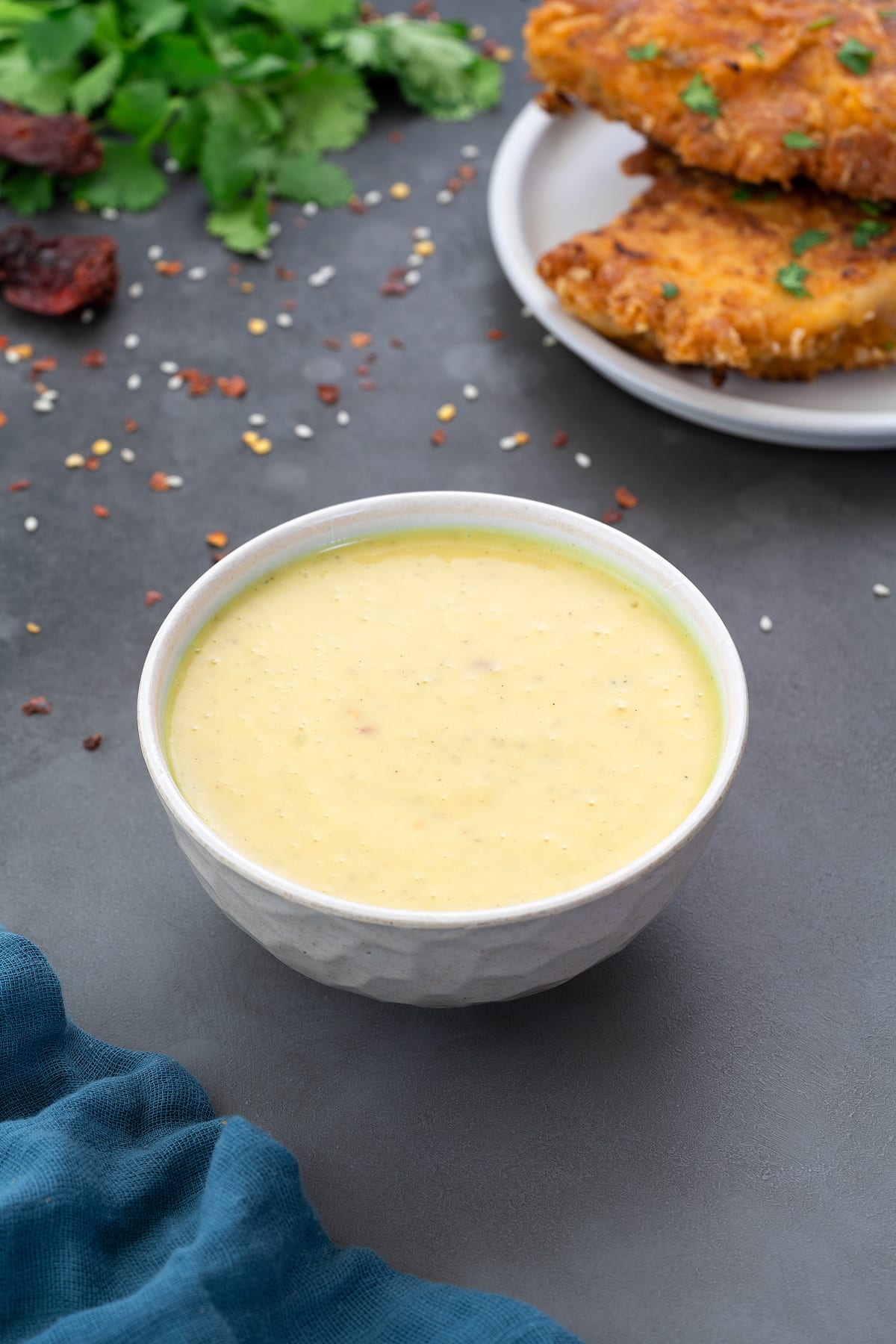 Homemade Honey Mustard Sauce in a white bowl with few ingredients scattered around.