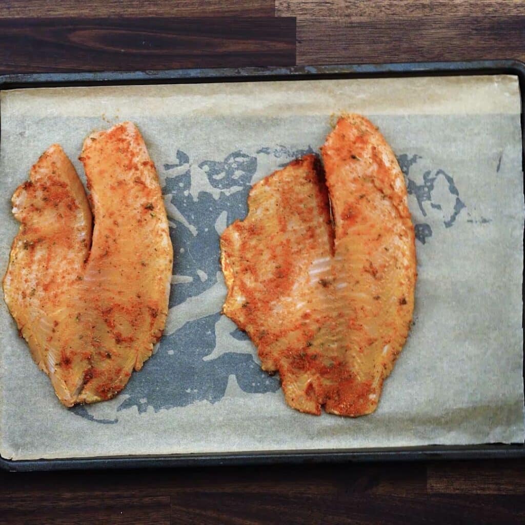 A tray with seasoned Tilapia fillets.
