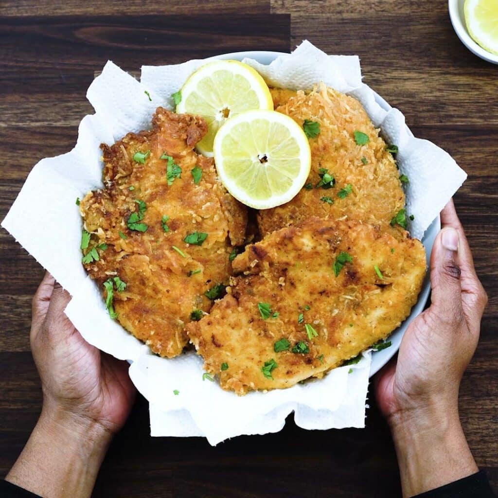 Serving Parmesan Crusted Chicken along with lemon slices.