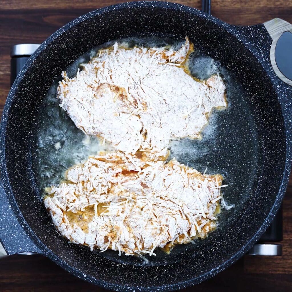 Frying the parmesan crusted chicken in oil.