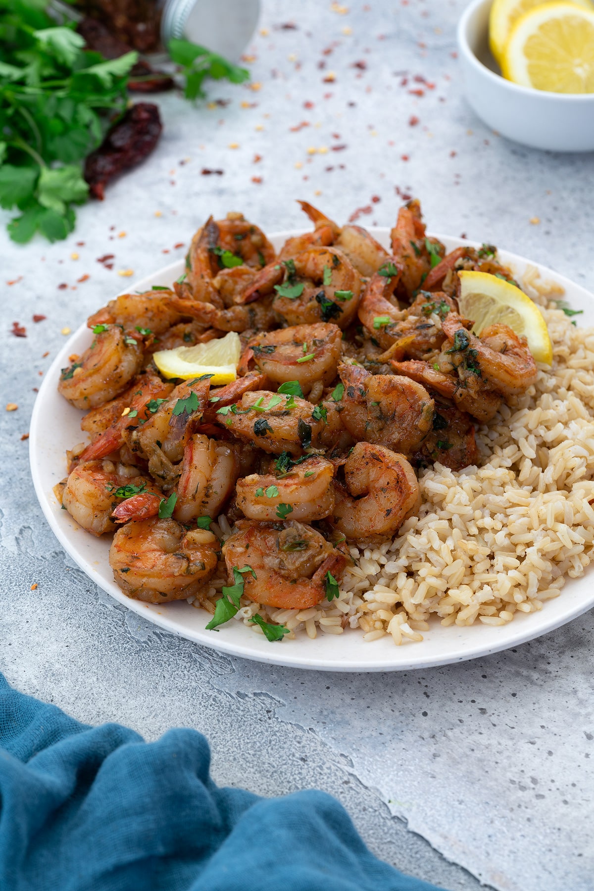 Sauteed Shrimp dish on a white plate with brown rice and garnish.