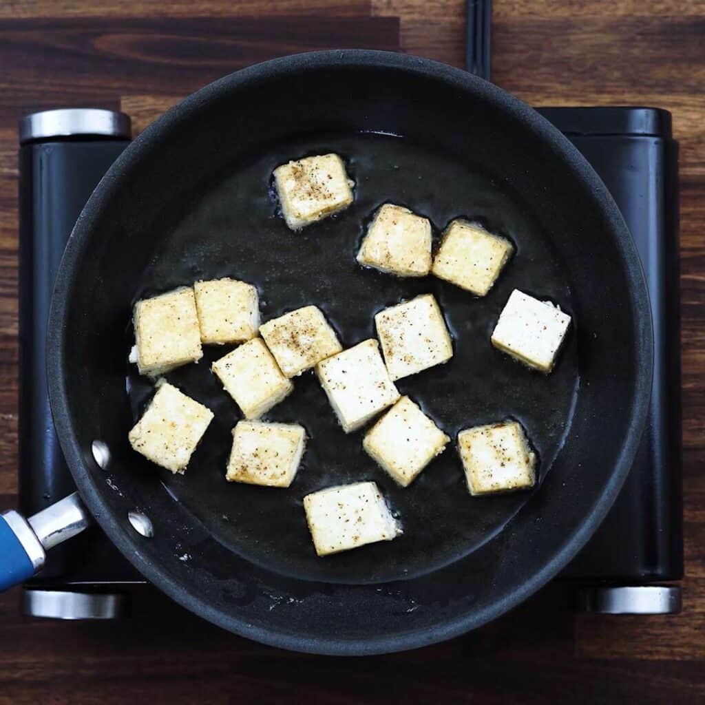A pan with tofu frying in oil.