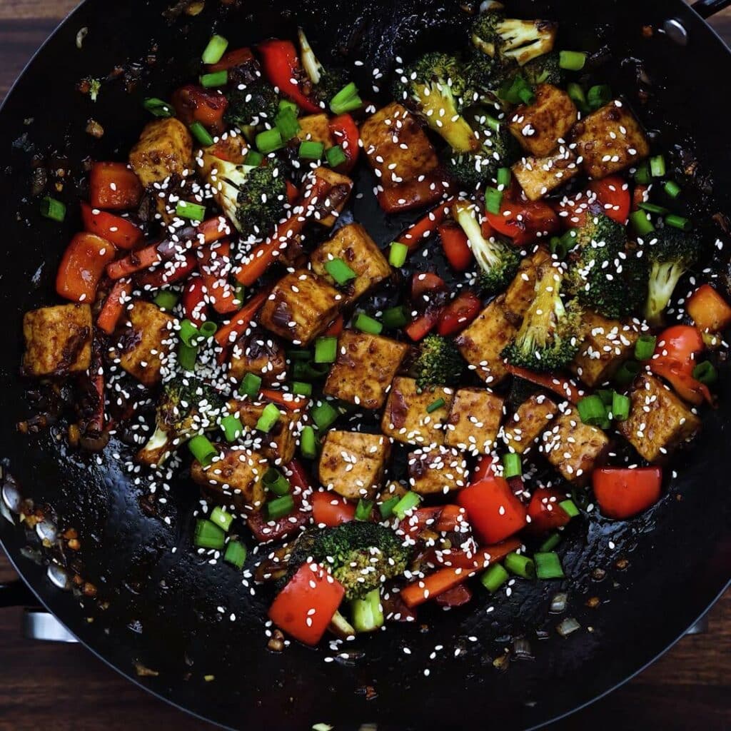 Stir fried tofu garnished with sesame seeds and spring onions.