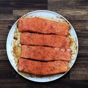 Blackening seasoning coated salmon fillets on a plate.