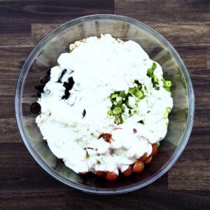 A bowl with chicken salad ingredients and dressing.