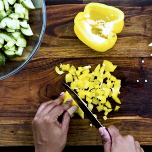 Dicing yellow bell pepper using knife.