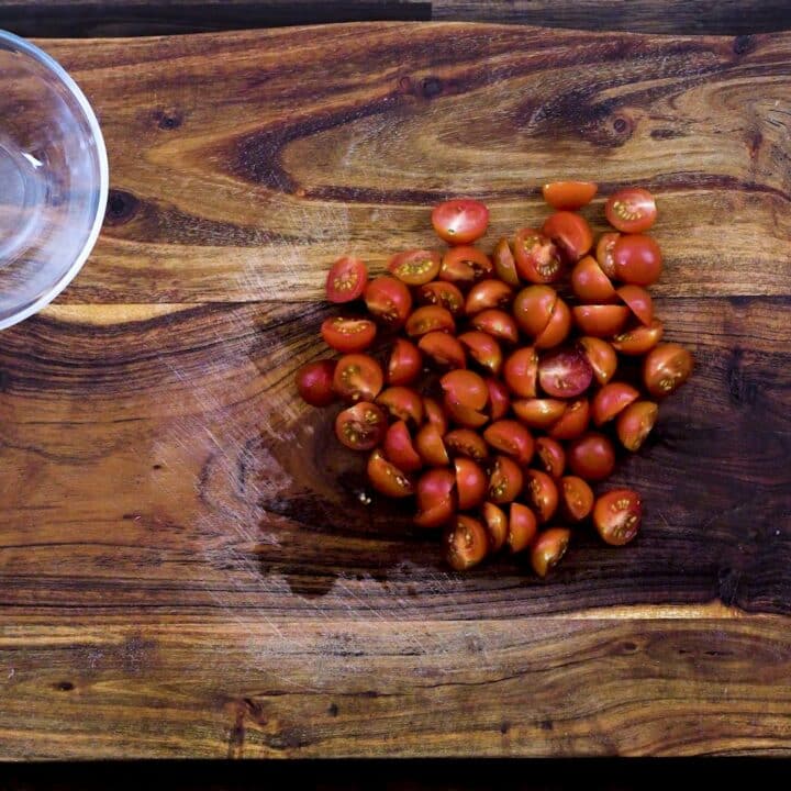 Halved cherry tomatoes on a cutting board.