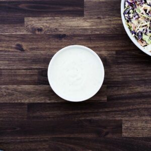 A white bowl with coleslaw salad dressing.