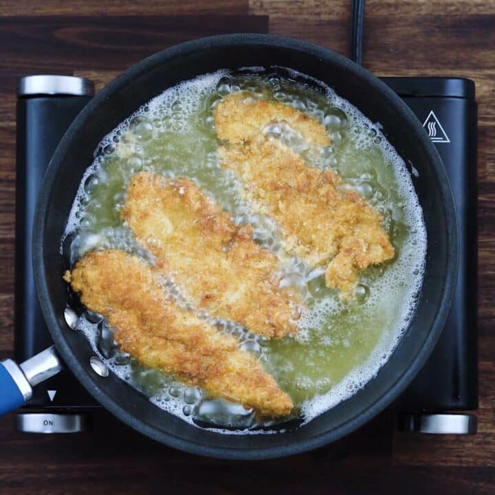 Golden fried chicken tender in a pan with oil.