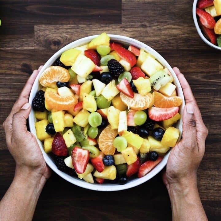 Serving the fruit salad in a white bowl.