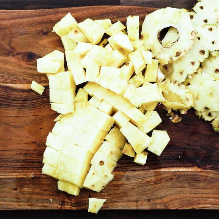 A bite size chopped pineapple on cutting board.