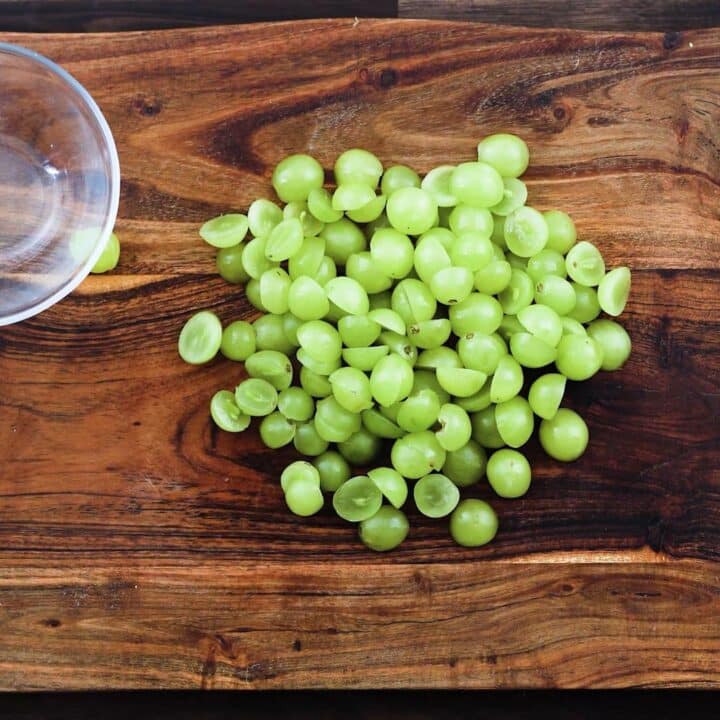 Sliced green grapes on a cutting board.