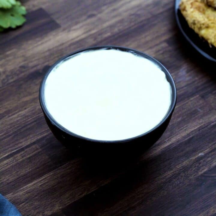 Mayonnaise served in a black bowl.